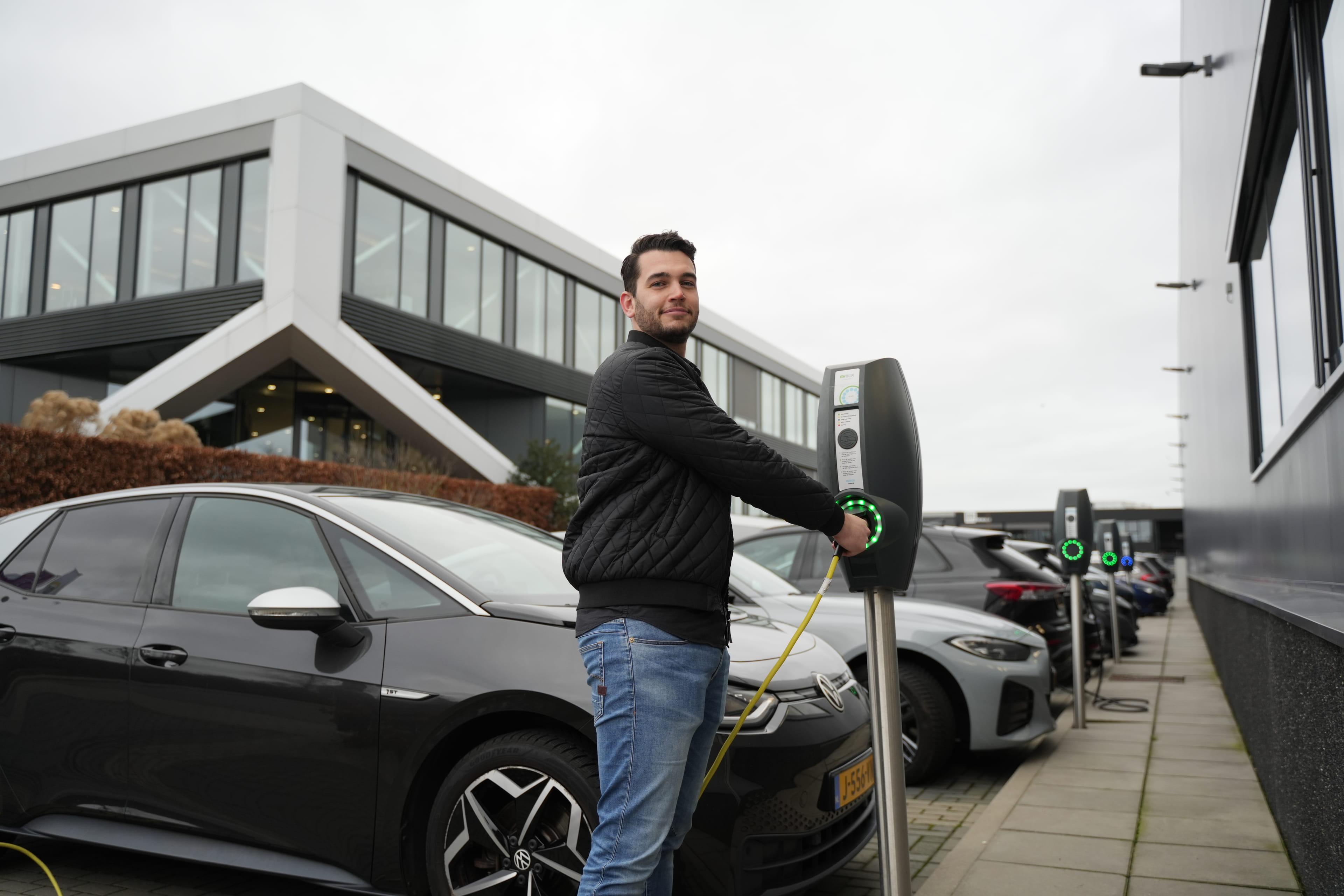 Man steekt de stekker van zijn elektrische auto in de oplaadpaal.